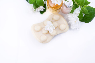 Soap with jasmine on a white background and fresh flowers. Beauty and care products in the spa. Free space for text. Copy space