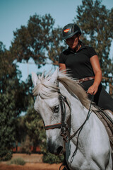 Caballo espa&ntilde;ol en una hipica en andalucia con su Jinete Amazona montandolo con sus riendas y saltando en una pista 