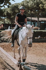 Caballo español en una hipica en andalucia con su Jinete Amazona montandolo con sus riendas y...