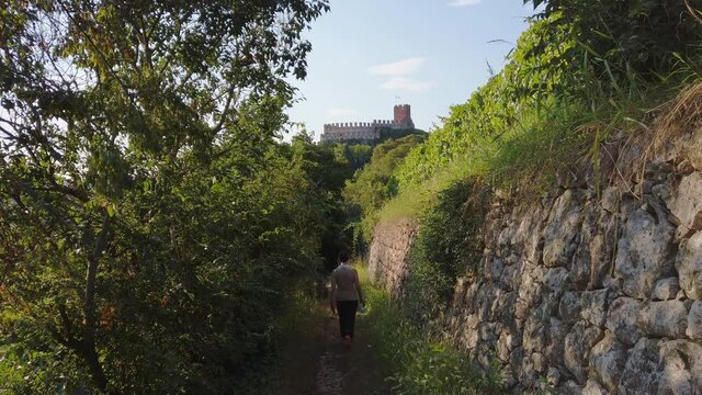 Woman hiking along a nature trail going toward the castle of Soave, Italy