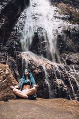 Young Caucasian girl under Diyaluma waterfall, Sri Lanka. Happy woman in meditation pose on...
