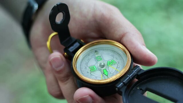 Man holds a compass in hand and looks for direction