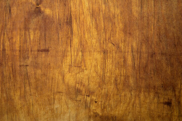 Yellowed wood texture of a kitchen Board with knife cuts
