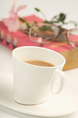 Close-up of a cup of tea with a book and a pair of eyeglasses