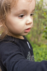 Criança pequena brincando no jardim. Menina brincando com as plantas e flores no jardim. 