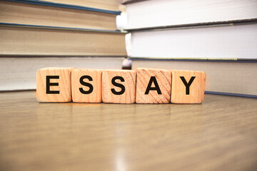 Essay words on wooden blocks with Books on blurred backround