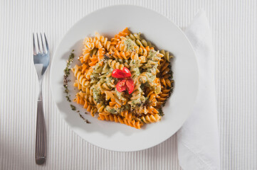 High angle view of a bowl of rotini topped with pesto sauce