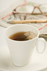 Close-up of a cup of tea with crossword puzzle and a pencil in the background