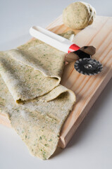 High angle view of dough with a pasta cutter on a cutting board