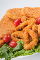 Close-up of crumb fried onion rings and cutlets with tomatoes
