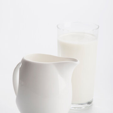 Close-up of a glass of milk and a white ceramic jug