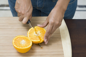 Mid section view of a woman cutting an orange