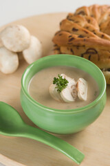 Bowl of soup served with mushroom and a loaf of bread