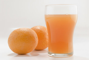 Close-up of two oranges with a glass of orange juice
