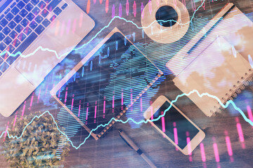 Double exposure of forex chart hologram over desktop with phone. Top view. Mobile trade platform concept.