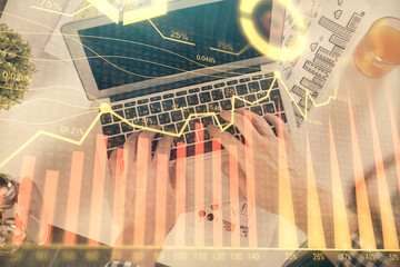 Double exposure of man's hands typing over laptop keyboard and forex chart hologram drawing. Top view. Financial markets concept.