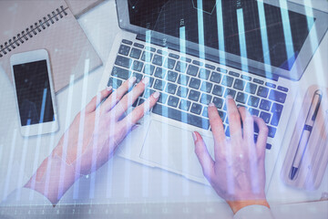 Double exposure of woman hands working on computer and forex graph hologram drawing. Top View. Financial analysis concept.
