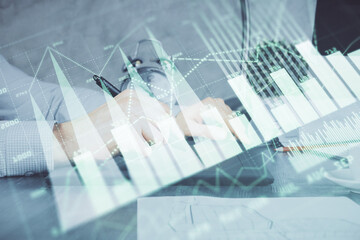 Double exposure of man's hands holding and using a phone and financial graph drawing. Analysis concept.