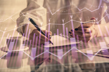 Double exposure of financial graph sketch hologram and woman holding and using a mobile device....