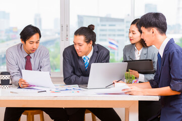 Business People Analyzing Statistics Financial Concept - Group of young confident business people analyzing data using computer in thailand.
