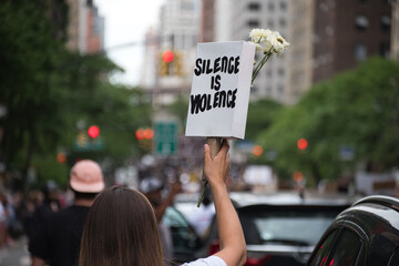 Woman holds up Silence is Violence sign at a Black Lives Matter protest march 