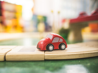 Portrait of red wooden car on wooden plate in toy room with blur background