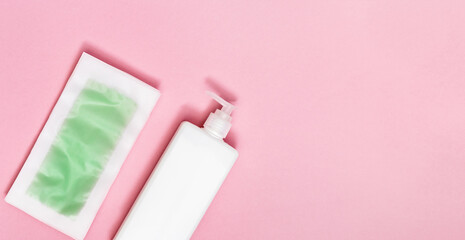 Green waxing strips with mint and cooling effect, body moisturizer on pink paper background with copy space. Flat lay.