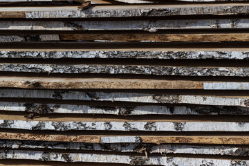 Wooden boards are laid to dry. A stack of natural boards, raw birch boards with birch bark, close-up with a blurred background. Natural raw wood texture, DIY construction