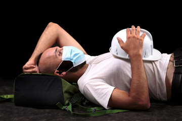 Obraz premium Young hispanic male construction worker with mask taking a siesta