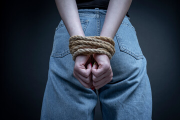 Young girl with bound hands on black background, close up