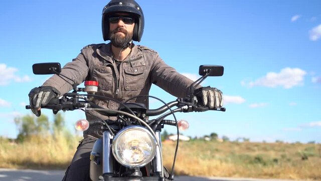 Dressed adult man with beaded sitting on motorbike ready for a ride on a sunny day