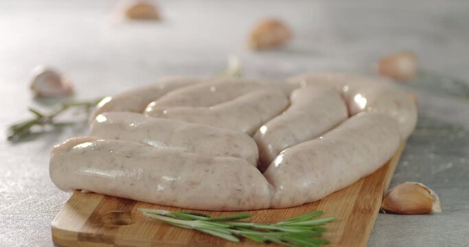Raw sausages with rosemary and garlic on the table rotate.
