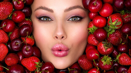 Young girl with bright makeup and a berry background. Beautiful caucasian woman. Attractive woman .