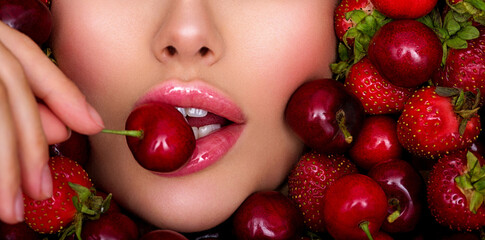 Attractive woman tasting cherry and strawberry. Beautiful woman with fashion makeup and a vivid...