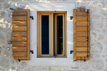 Obraz na płótnie Canvas Wooden window with shutters in a stone house.