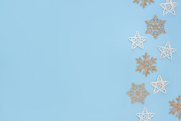 Golden snowflakes and rattan stars on pastel blue background. Minimal concept of Christmas and New Year. Copy space, flat lay