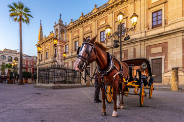 Naklejka na ściany i meble Seville, Spain. October 15th, 2020. Horse-drawn carriage waiting for tourists on Calle Miguel Mañara in front of the facade of the Archivo General de Indias building.