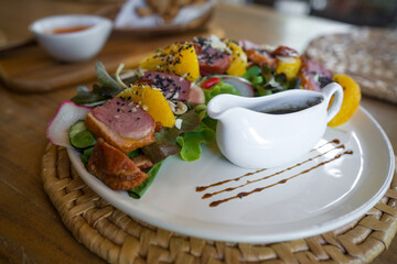 Smoked duck breast salad with brown sauce served on wooden table