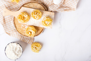 Fototapeta na wymiar Italian rolled fresh fettuccine pasta with flour on white background.