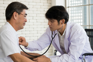 Young male doctor checking up senior man patient health at hospital room.