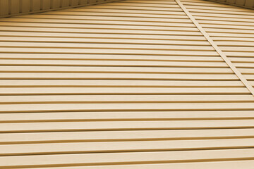 Striped plastic siding surface and piece of cornice. Construction and renovation of buildings. Tinted light brown background or wallpaper. Building materials or technologies