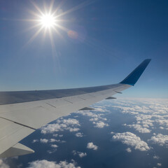 Obraz premium view from an airplane to a cloudy sky and sparkle sun, travel background