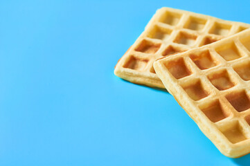 Two vanilla belgian waffles on blue background