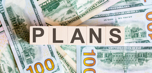 Concept words PLANS on wooden blocks on a beautiful background from dollar bills.