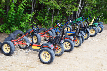 Many pedal kart for rent or sharing outdoors in city park, garden or forest. Healthy family outside sport recreation activities. Fun children cycle transport.
