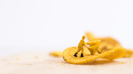 Miniature people, Workers work on  production potato chips on white background (food concept)