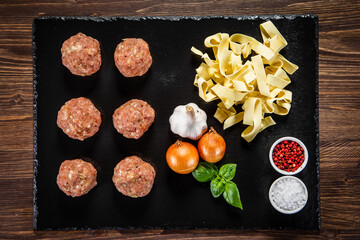 Raw meatballs on black stone board
