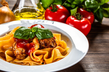 Pasta with meatballs in tomato sauce on wooden background
