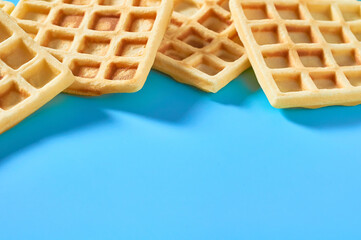 Scattered vanilla belgian waffles on blue background
