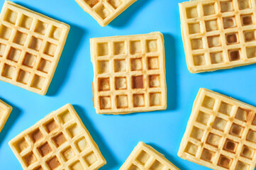 Scattered vanilla belgian waffles on blue background